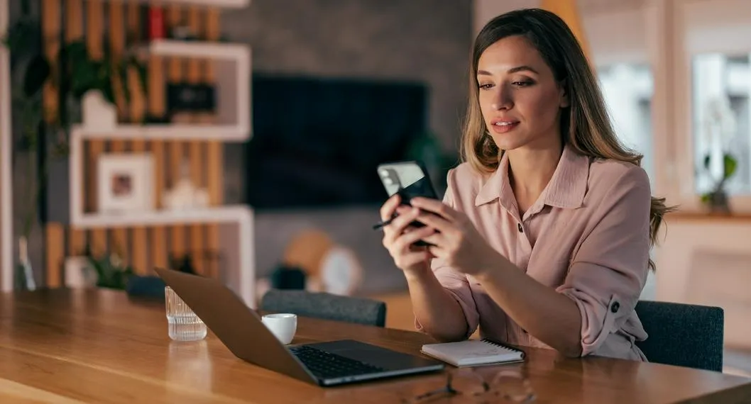 Mujer en el celular a propósito de cómo hacer para que le lleguen las notificaciones a WhatsApp.