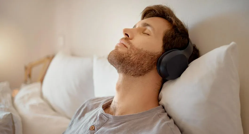 Joven escuchando música, relajado en su cama a propósito de cómo poner una canción de Spotify como alarma.
