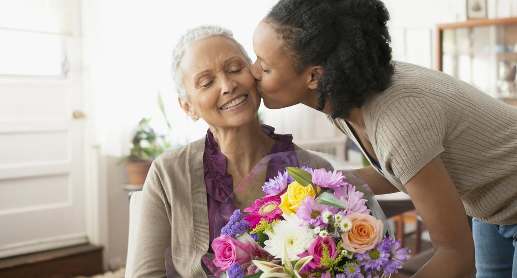 Mujer le regala flores a su madre a propósito de cómo cuidarlas.