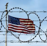 Bandera de Estados Unidos frente a un alambrado que representa el muro fronterizo con México