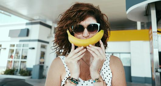 Mujer sosteniendo un banano a propósito de los beneficios de esta fruta.