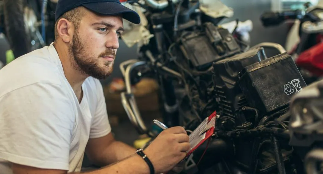 Persona revisando la moto a propósito de cómo evitar que se calienten estos vehículos y cuáles son las soluciones que se deben aplicar.