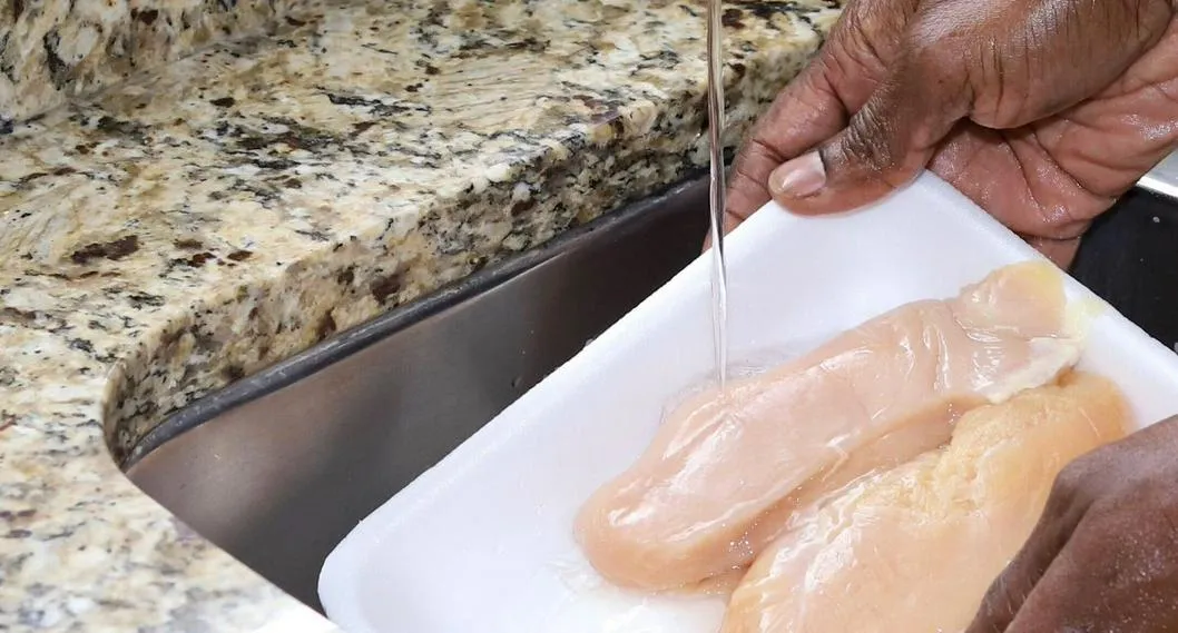 Hombre lavando el pollo a propósito de cómo lavar el pollo.