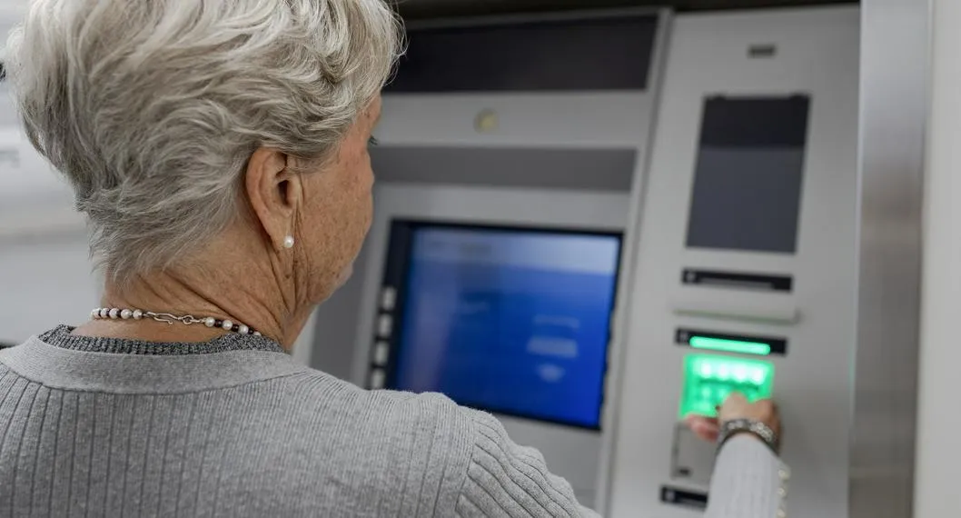 Over the shoulder close up senior woman using ATM in bank