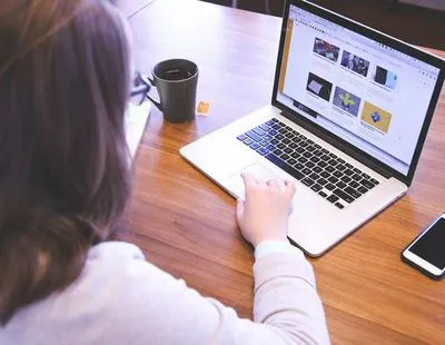 Mujer en computador. En relación con becas para bogotanos.