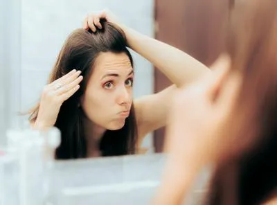 Mujer mirándose al espejo las canas. En relación con prevención.