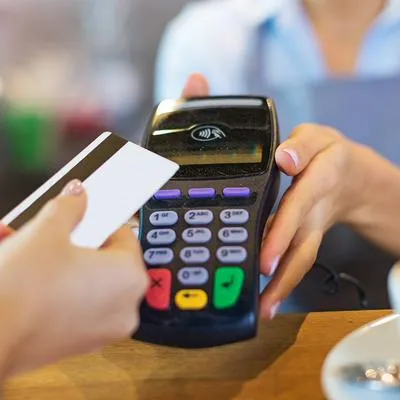 Mujer pagando con tarjeta de crédito, en nota sobre plásticos que dan puntos para comprar ropa y hasta viajes