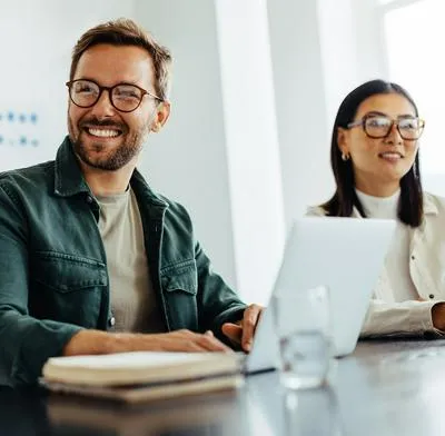 Happy business man listening to a discussion in an office boardroom. Business professional sitting in a meeting with his colleagues.