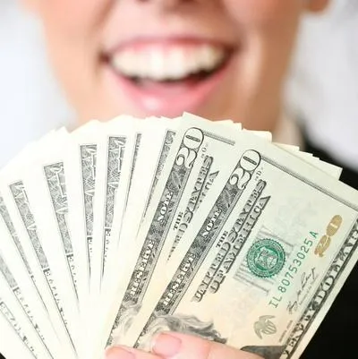 Persona sonriendo con dólares, por regalo que hizo que el dólar se cayer en Colombia