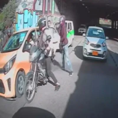 Motoladrones aprovecharon trancón en Bogotá para robar a conductor de taxi y su pasajera en calle 80 y a plena luz del día. 