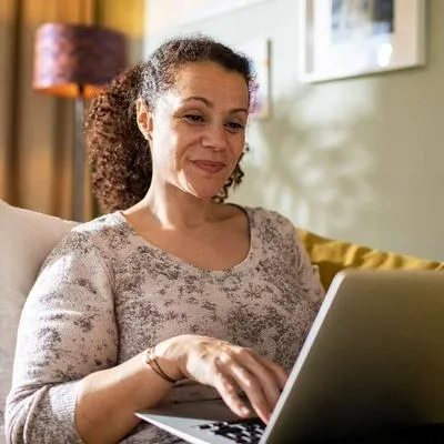 Foto de persona feliz frente a computador, en nota de que Colpensiones sacó solución para aportes a pensiones por períodos omisos de pago