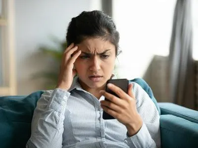 Mujer estresada con el celular. en relación con estafas desde aplicaciones.