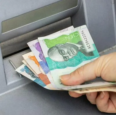 Persona sacando dinero de un cajero, a propósito de problemas y cobros que hacen bancos en Colombia