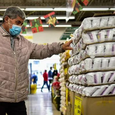 Hombre mirando precios en un supermercado, a propósito de las 10 marcas más consumidas en Colombia