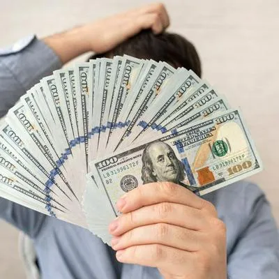 Hombre sosteniendo dólares, por precio que subió este 25 de julio de 2023