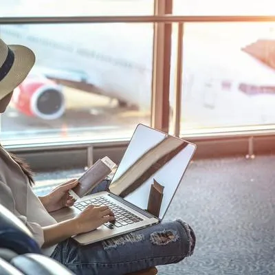Persona con computador en aeropuerto, en nota sobre pc que no se pueden llevar a Estados Unidos en avión