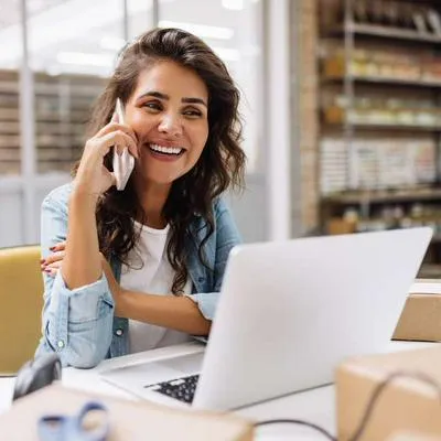 Foto de mujer sonriente frente a computador, en nota de que Colpensiones dio anuncio sobre pensión de emprendedores en Colombia con programa