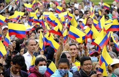 Marcha con bandera de Colombia. En relación con manifestación en Bogotá y Medellín.
