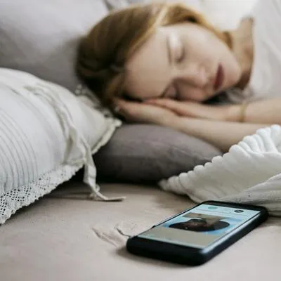 Mujer durmiendo con el celular. Apple avisó de las consecuencias que esto tiene en la salud.