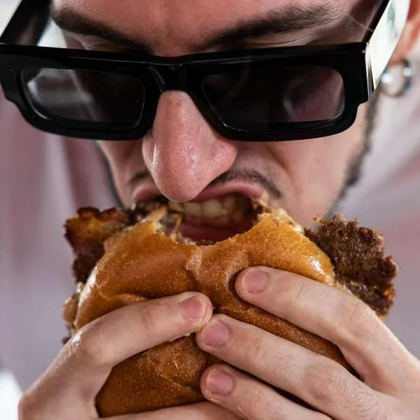 Foto de hombre comiendo hamburguesa, en nota de Home Burgers y por qué asusta a El Corral, McDonalds y Burger King en Colombia.