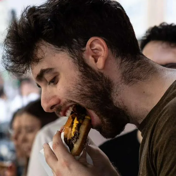 Foto de persona comiendo hamburguesa, en nota de que El Corral, McDonald's y Burger King sufren por fórmula de Home Burgers: cómo es