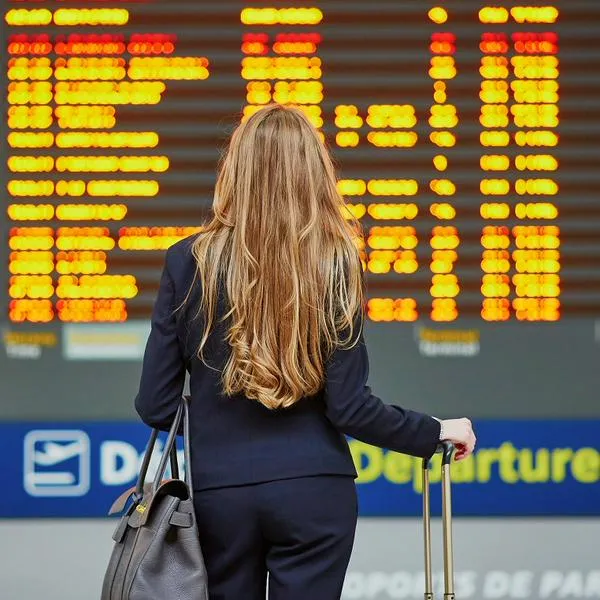 Mujer mirando pantalla de aeropuerto, en nota sobre países a donde puede ir sin pasaporte y con cédula