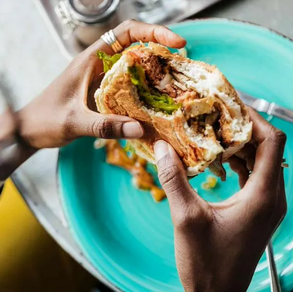 Foto de persona comiendo hamburguesa, en nota de cómo cuidarse de diabetes al comer en restaurantes como El Corral y McDonald's.