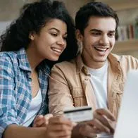 Foto de pareja sonriente frente a computador, en nota de cómo comprar tiquetes más baratos en Avianca, Latam y más en Colombia (video)