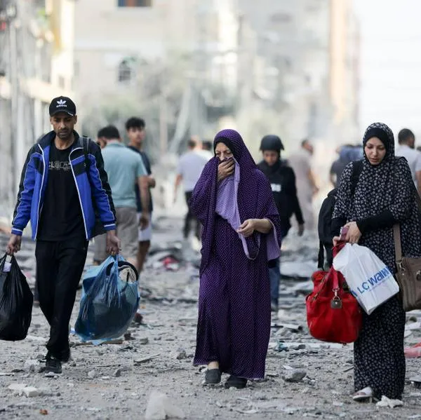 Palestinos caminan con algunas de sus pertenencias entre los escombros de las calles de la Franja de Gaza.