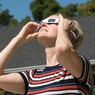 Mujer mirando eclipse solar, en nota sobre por qué no usar gafas de cine para verlo