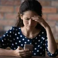 Foto de mujer preocupada con celular, en nota de alerta de Colpensiones sobre cómo es engaño en WhatsApp por datos y qué hacer