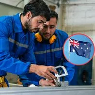 Hombres trabajando en una industria y de fondo una bandera de Australia. En relación a el tiempo que se puede estar en el país siendo colombianos y documentos que se necesitan.