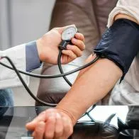 Persona siendo atendida por un doctor que le está tomando la tensión. 