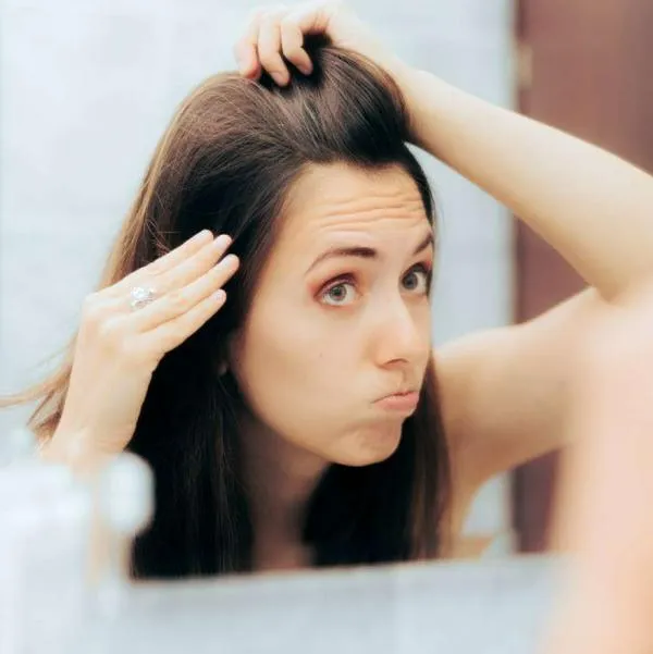 Foto de mujer viendo su cabeza, en nota de que para Caída del cabello, dieta de alimentos y vitaminas que sirven para combatir ese problema
