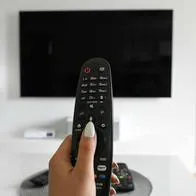 Foto de persona con televisión, en nota de pantalla del televisor: por qué se daña, cómo solucionar problemas y cuánto duran