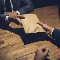 Hombre dando dinero a tro en intento de soborno. Percepción de la corrupción en Colombia disminuyó, pero falta: en qué trabajar