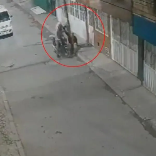Momento en el que unos delincuentes en Bogotá atracan y golpean a un hombre en una calle. Uno de los ladrones llevaba una maleta de domiciliario