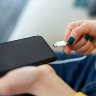 Foto de mujer cargando dispositivo, en nota de cuánto tiempo cargar un celular por primera vez: clave para no dañar la batería