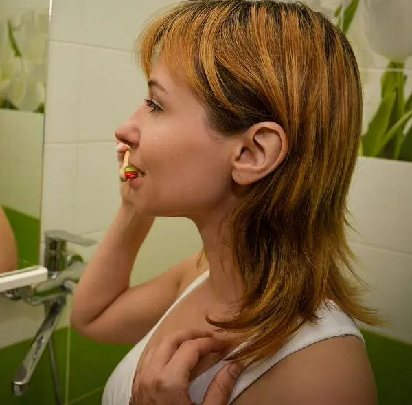 Foto de mujer cepillado dentadura, en nota sobre cuántas veces hay que lavarse los dientes al día: recomendaciones y mito que es dañino
