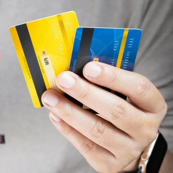 Imagen de tarjetas de crédito y dinero por nota sobre baja en tasas de interés.