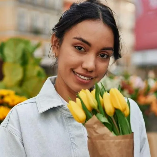 Foto de mujer con flores amarillas, en nota de por qué se regalan el 21 de marzo y cuál es su significado clave