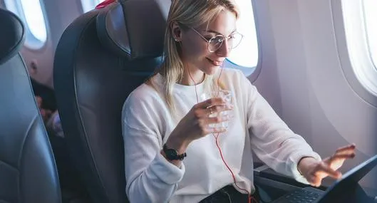 Mujer utilizando computador en un avión, en nota sobre cómo hay Internet en las aeronaves