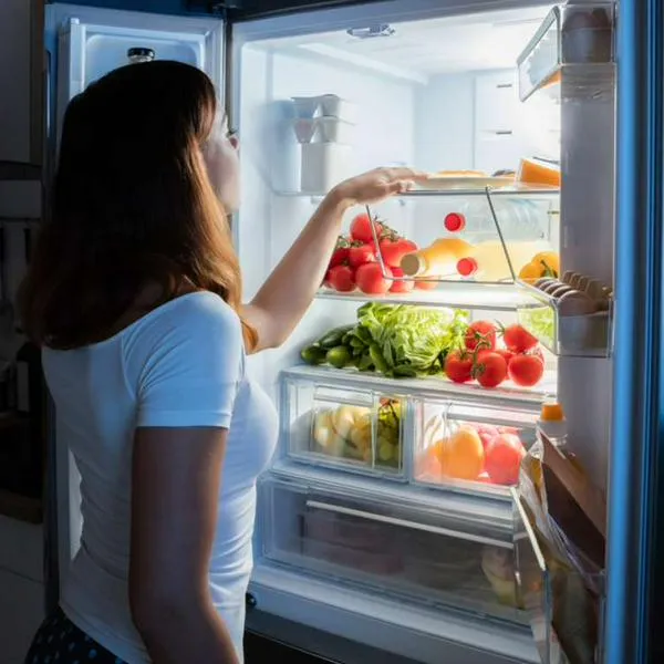 Foto de mujer ante refrigerador, en nota de por qué la nevera hace ruidos y cómo eliminarlos con trucos caseros muy simples