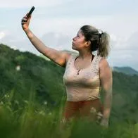Foto de mujer buscando señal, en nota de qué hacer cuando el celular dice sin servicio.
