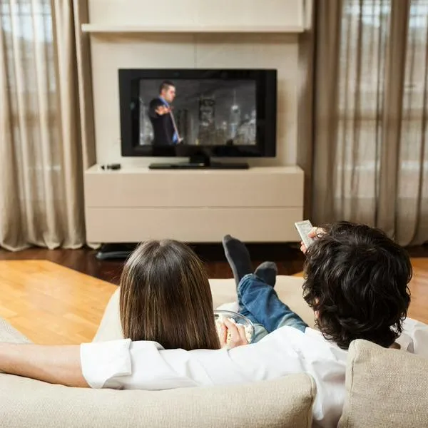 Personas viendo televisión en nota sobre cómo tener más canales en el televisor