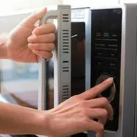 Foto de mujer en cocina, en nota de qué bebidas no se deben meter en el microondas.
