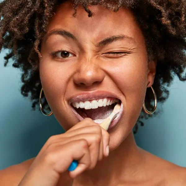 Imagen de mujer cepillándose los dientes por nota sobre pregunta alrededor del cepillado