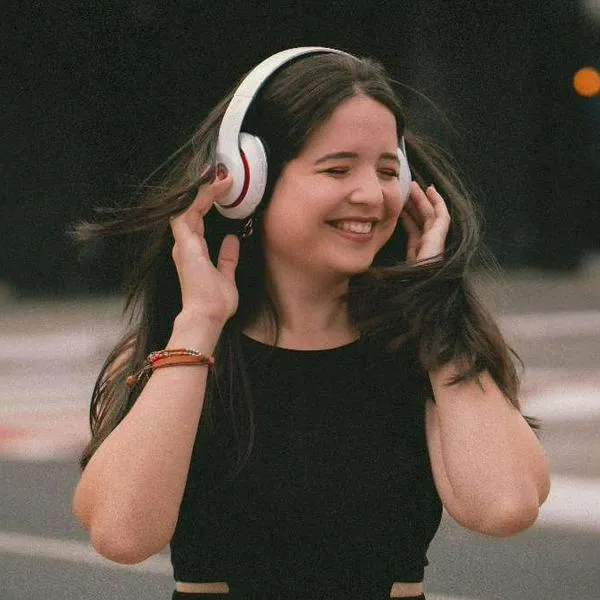 Foto de mujer escuchando auriculares, en nota de cómo se limpian los audífonos inalámbricos sin dañarlos y con pasos muy fáciles