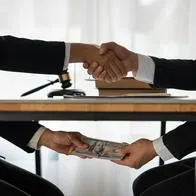 Imagen ilustrativa de un trato por debajo de la mesa, corrupción o fraude.