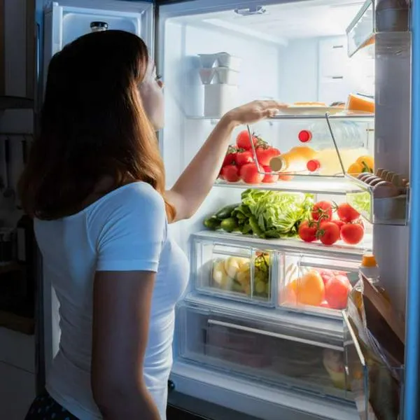 Foto de mujer viendo comida, en nota de por qué la nevera enfría arriba y abajo no: razón detrás y así puede resolverse